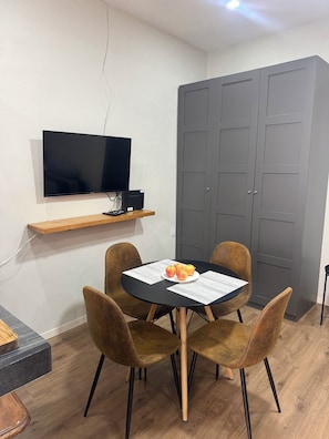 A room with a dining table, four chairs, a television mounted on the wall, and a grey door. - Private Studio Near Condesa, Roma & Chapultepec (Ciudad de México)