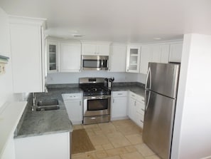 A modern kitchen with white cabinets, stainless steel appliances, and a granite countertop. - Ocean side 6 houses to the beach; 4 bed with full SUNSET views (Beach Haven)