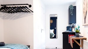 Ein gemütlicher Raum mit Bett, Spiegel, einer kleinen Küchenzeile und einer Kleiderstange.