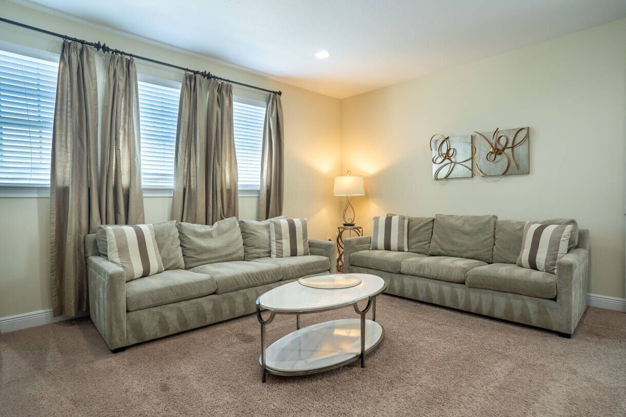A living room with two sofas, a round coffee table, a lamp, and abstract wall art.