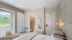 Ein Schlafzimmer mit einem großen Bett, einem Nachttisch mit einer Flasche, einem Spiegel und einer Tür zum Badezimmer.