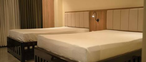 Two single beds with wooden frames and headboards, a bedside table, and a lamp on the wall.