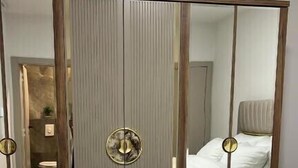 A bedroom with a bed, a mirror, and a wardrobe.