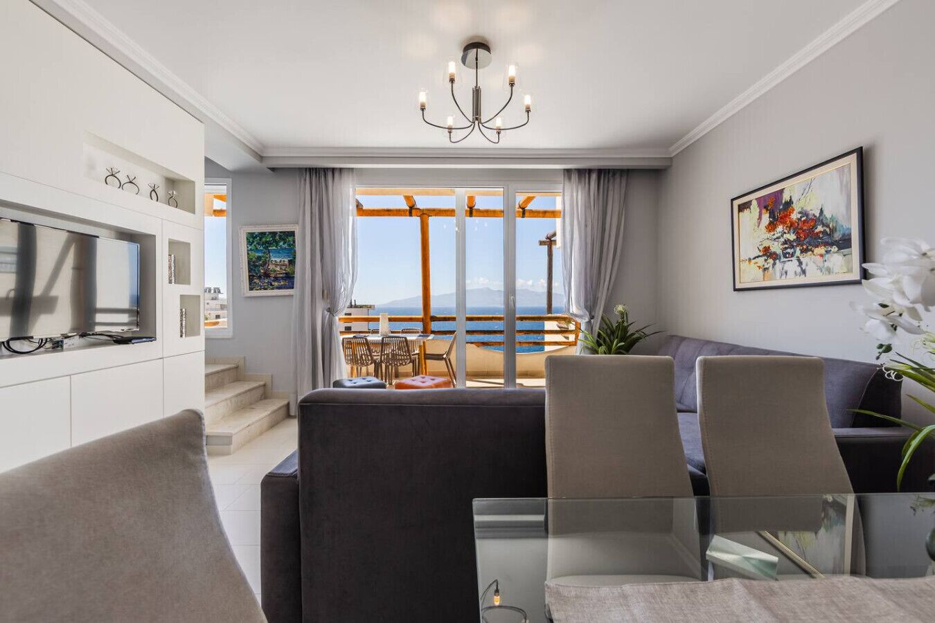 En moderne stue med TV, siddepladser og en balkon med udsigt.