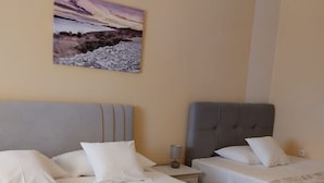 A hotel room with two beds, a nightstand, a lamp, and a painting on the wall. - Holiday Home Katica in Okrug Gornji (Okrug Gornji)