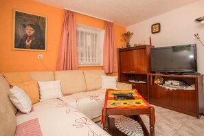 Una sala de estar con un sofá, una mesa de centro de madera, un televisor y un cuadro en la pared.