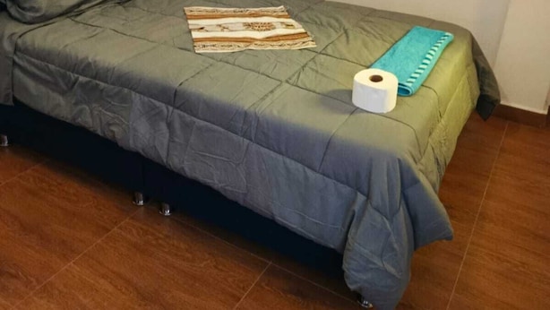 Un letto singolo con una testiera blu, una coperta verde e una coperta decorata.