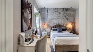 A modern bedroom with a large bed, bedside tables, a desk, and a large painting.