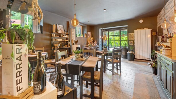 A spacious kitchen with wooden tables, hanging light fixtures, and a view of the outdoors.
