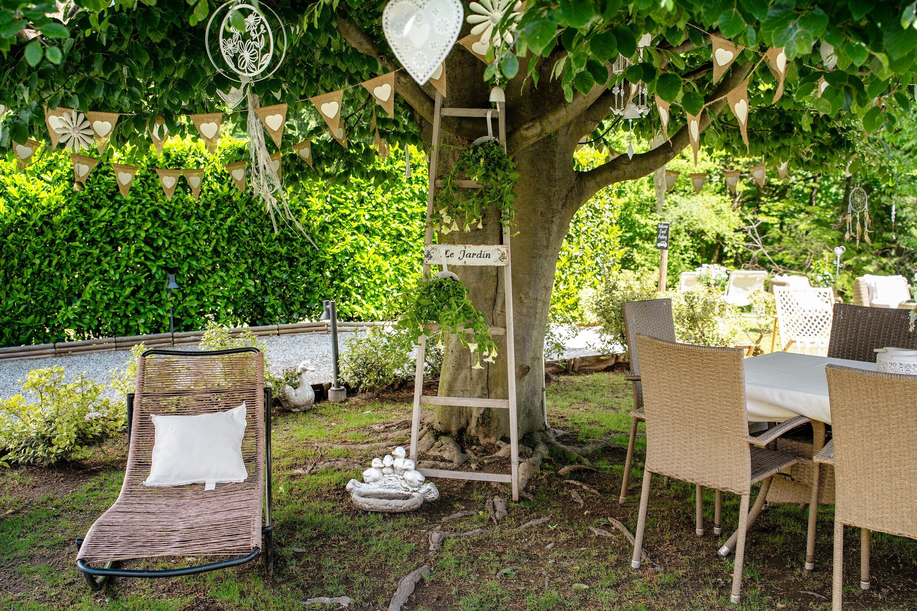 A garden with wicker furniture, a ladder, and a sign reading 'Le Jardin'.