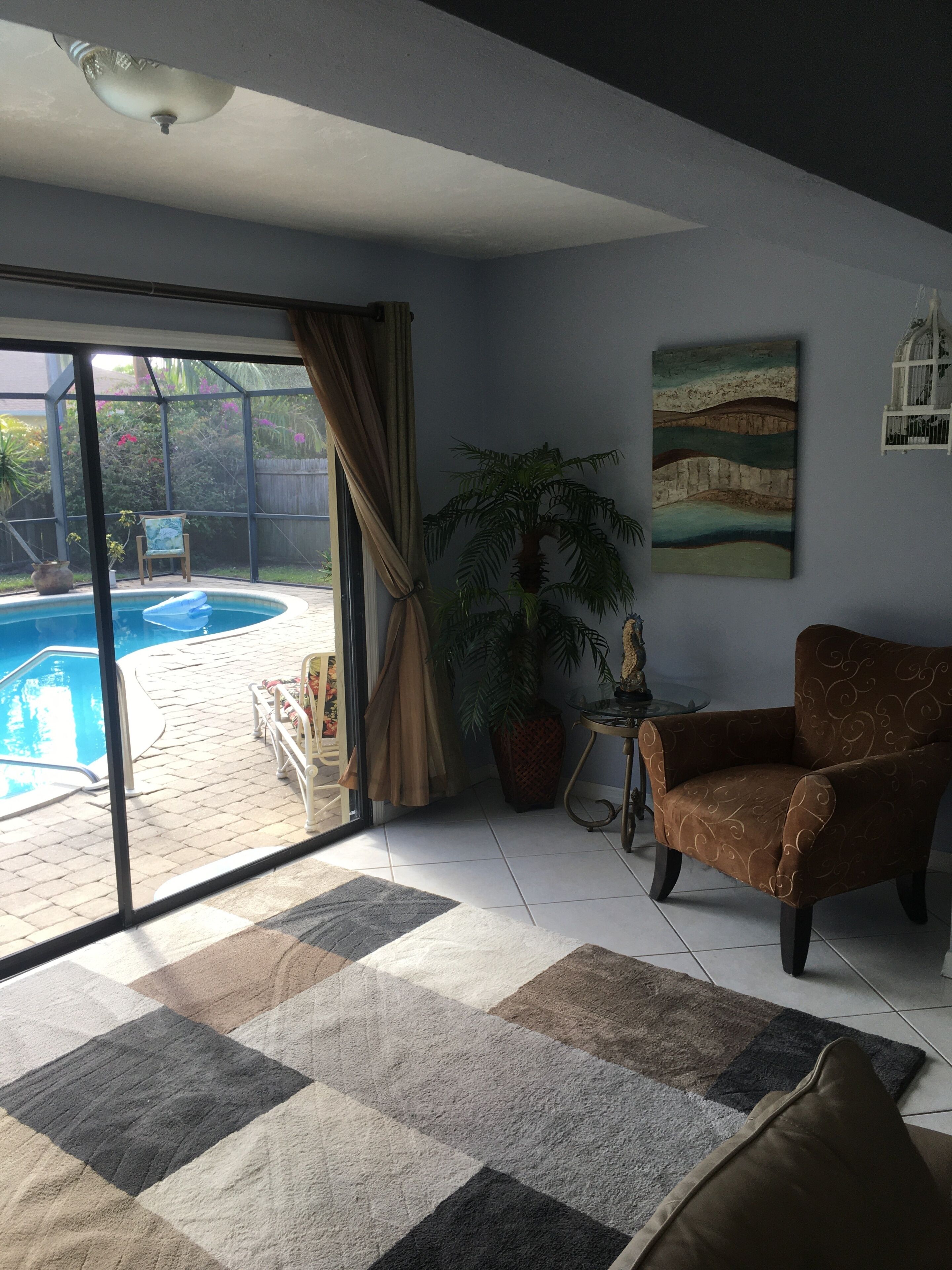 Un soggiorno con piscina, una sedia, un tavolo e un quadro.