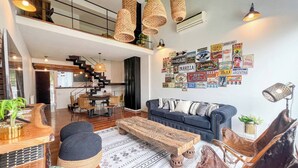 Un interior moderno con una escalera, zona de comedor y una pared decorada con carteles antiguos.