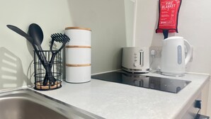 Uma cozinha com pia, cafeteira, torradeira e manta anti-incêndio no balcão.