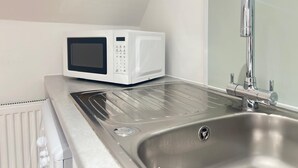 Uma cozinha compacta com micro-ondas, pia e janela.