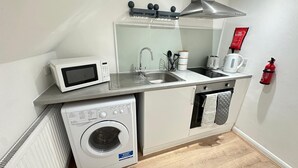 Uma cozinha compacta com micro-ondas, pia, torradeira e máquina de lavar.