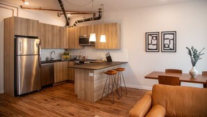 Cozinha moderna com armários de madeira, eletrodomésticos de aço inoxidável e uma ilha central com banquetas.
