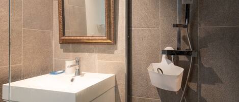 A bathroom with a white sink, a mirror with a gold frame, and a shower with a handheld showerhead.