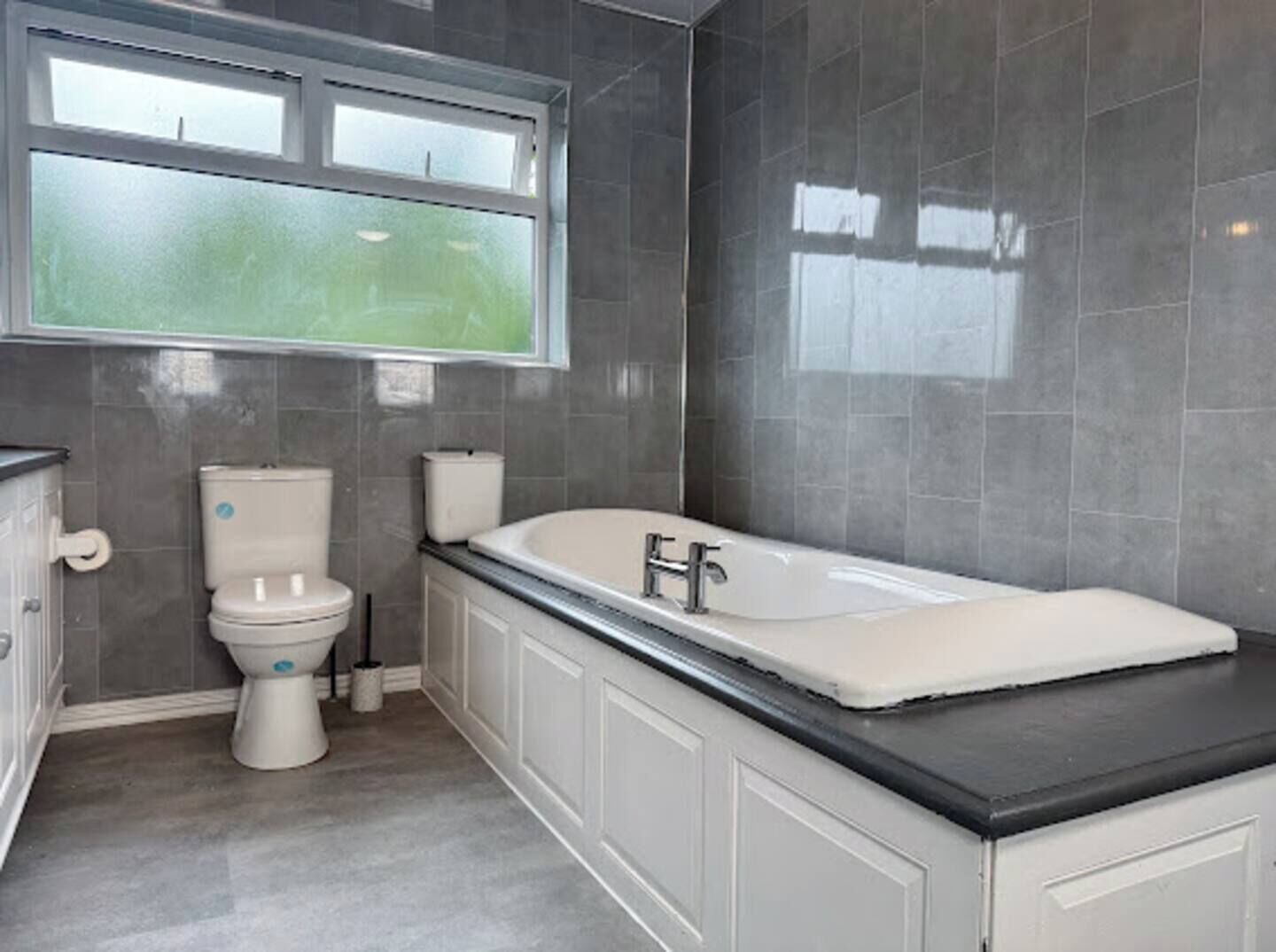 Une salle de bain avec des toilettes, une baignoire et une fenêtre.