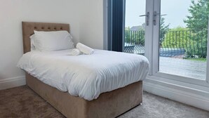 Een slaapkamer met een bed, een raam en uitzicht op een balkon.