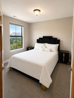 A bedroom with a large bed, a nightstand, a window with a view, and a ceiling light. - Downtown Atlanta Loft, 1 Block to Mercedes-Benz Stadium, FREE Parking (Atlanta)