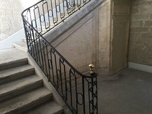 Een trap met een zwarte metalen leuning en een messing handgreep.