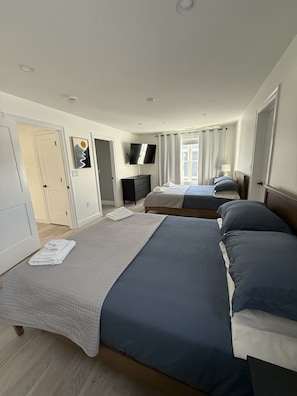 A hotel room with two beds, a TV, a desk, and a window with curtains. - White Mountains Golf & Ski House at Owls Nest Resort & Spa (Thornton)
