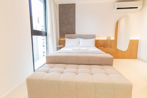Ein modernes Schlafzimmer mit einem großen Bett, einer Sitzecke, einer Wand in Holzoptik und einer Klimaanlage.