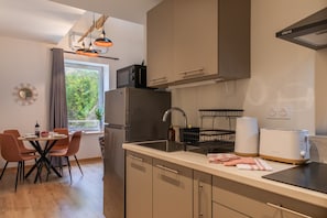 Une cuisine moderne équipée d’un four encastré, d’un évier et d’un coin repas avec une table et des chaises.