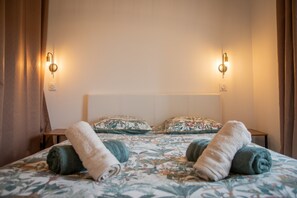 Hotellihuone, jossa on sänky, kaksi seinään kiinnitettyä valaisinta ja yöpöytä.