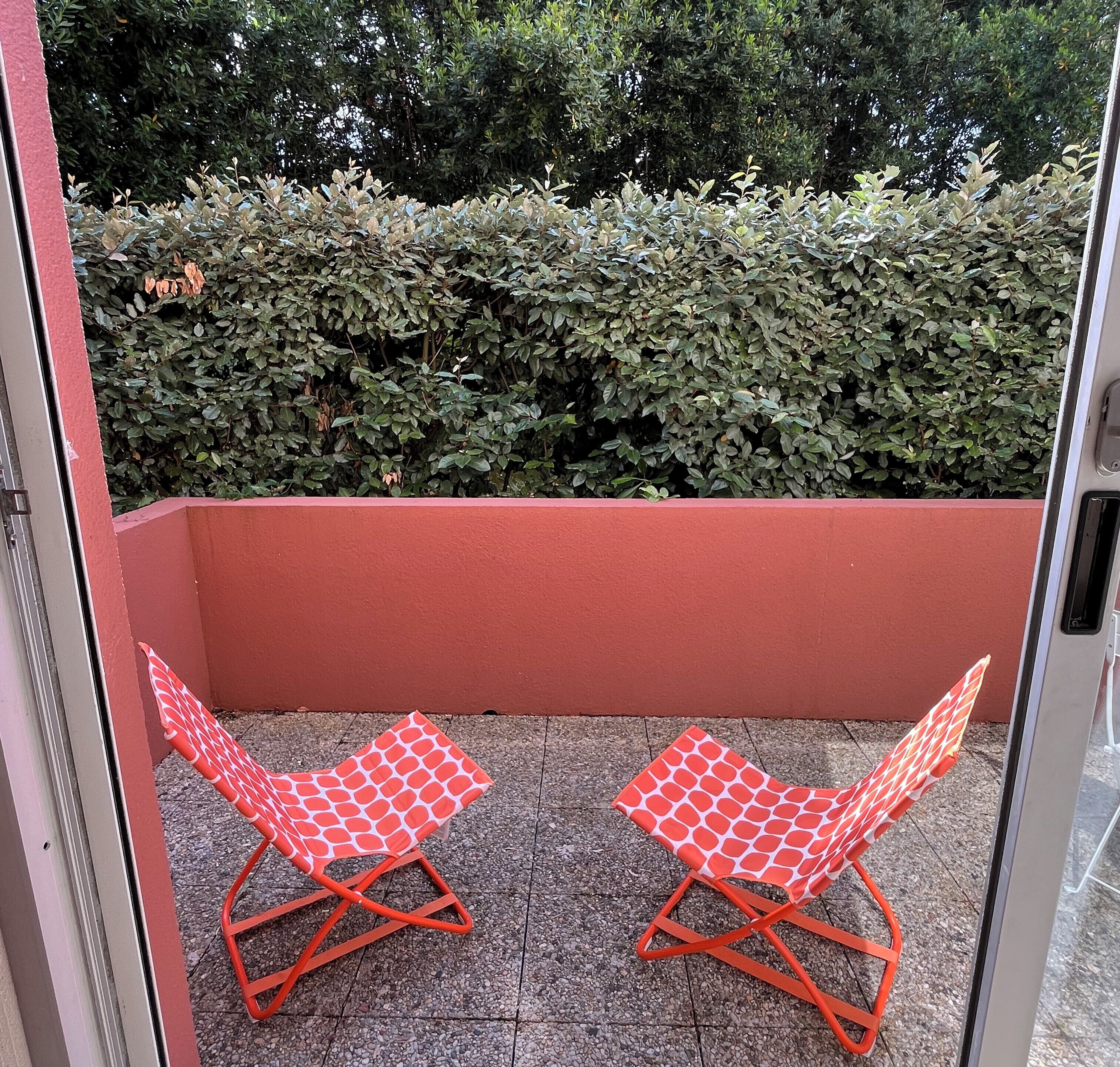 Un balcon avec deux chaises pliantes rouges et un mur rouge.