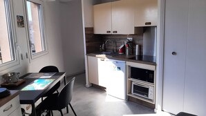 Uma cozinha compacta com área de refeições, micro-ondas e pia.