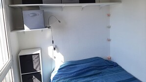 Quarto com cama, janela e estantes embutidas com caixas de armazenamento.