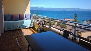 A balcony with a sofa, a table, and a view of the sea. - Apartment with Panoramic Sea View (Ajaccio)