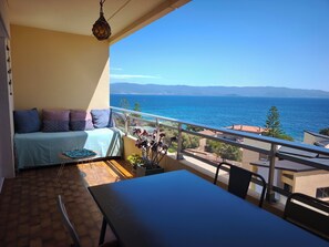 A balcony with a sofa, a table, and a view of the sea. - Apartment with Panoramic Sea View (Ajaccio)