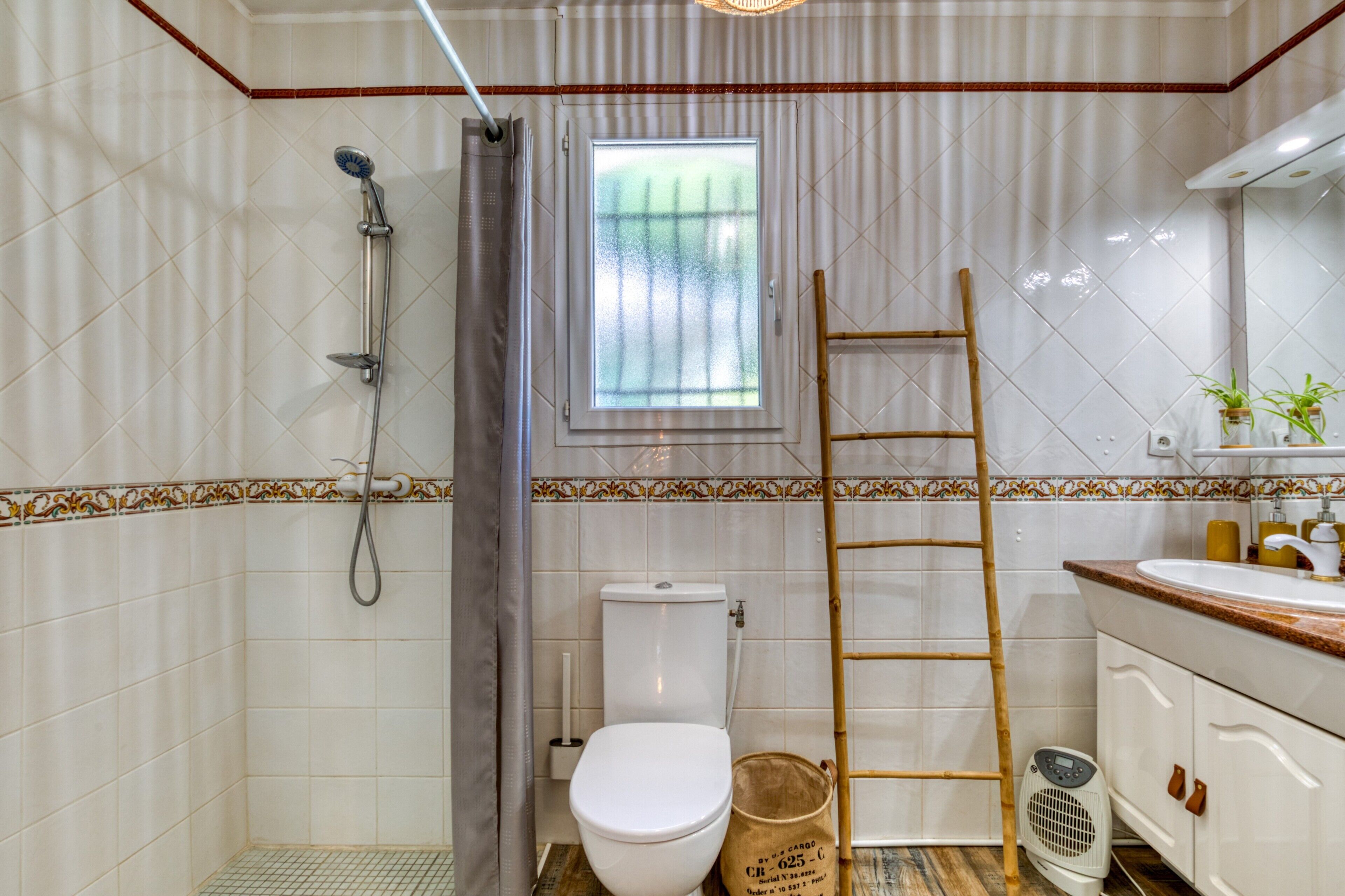A bathroom with a toilet, shower, and a window.