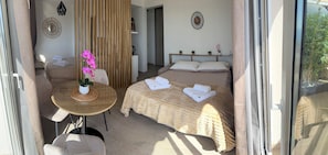 A room with a bed, a table with a potted plant, a chair, and a window. - BEAUTIFUL STUDIO SLEEPS 4 SEA VIEW CANNES (Cannes)