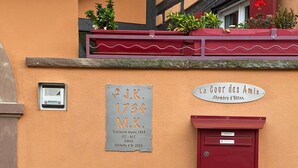 Un edificio con una placa que reza 'J.K. 1734 M.K.' y un letrero que dice 'La Cour des Amis'.