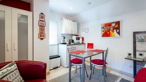 Un espacio habitable compacto con comedor, kitchenette y un sofá rojo.