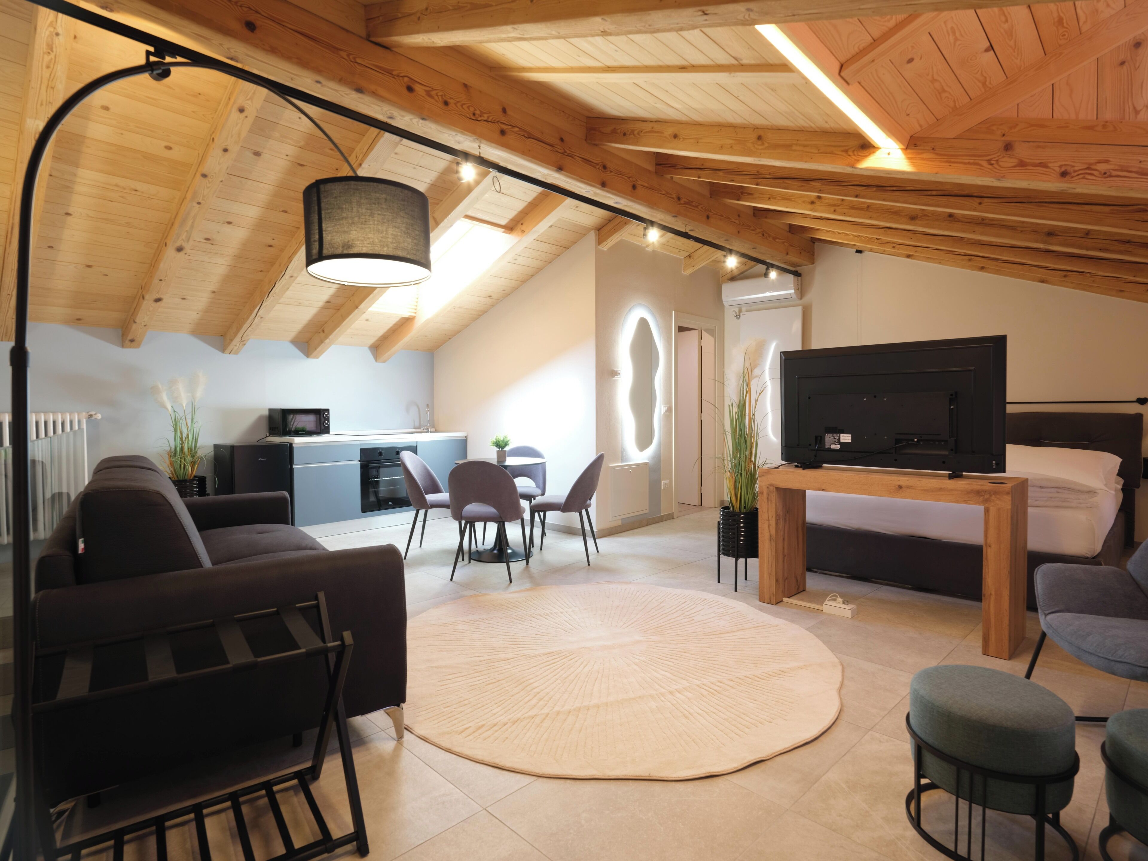 A modern loft-style living space with a kitchen, dining area, and a bedroom.