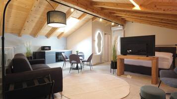 A modern loft-style living space with a kitchen, dining area, and a bedroom.