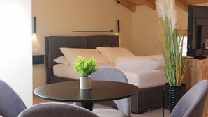 A modern bedroom with a bed, a small round table with a plant, and a TV. - Soul of Trento Vicolo Maddalena (Trento)