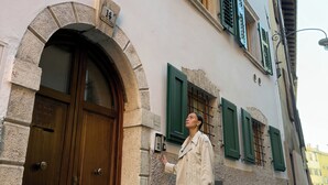 A building with a stone archway entrance, wooden doors, and green shutters. - Soul of Trento Vicolo Maddalena (Trento)