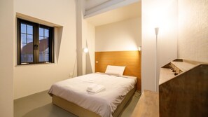 A bedroom with a bed, a window, a bedside lamp, and a wooden headboard.