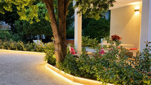 A landscaped outdoor area with a gravel path, trees, and a seating area with a table and chairs.