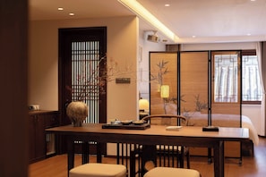 A modern hotel room with a dining area, a large vase, and traditional decor.