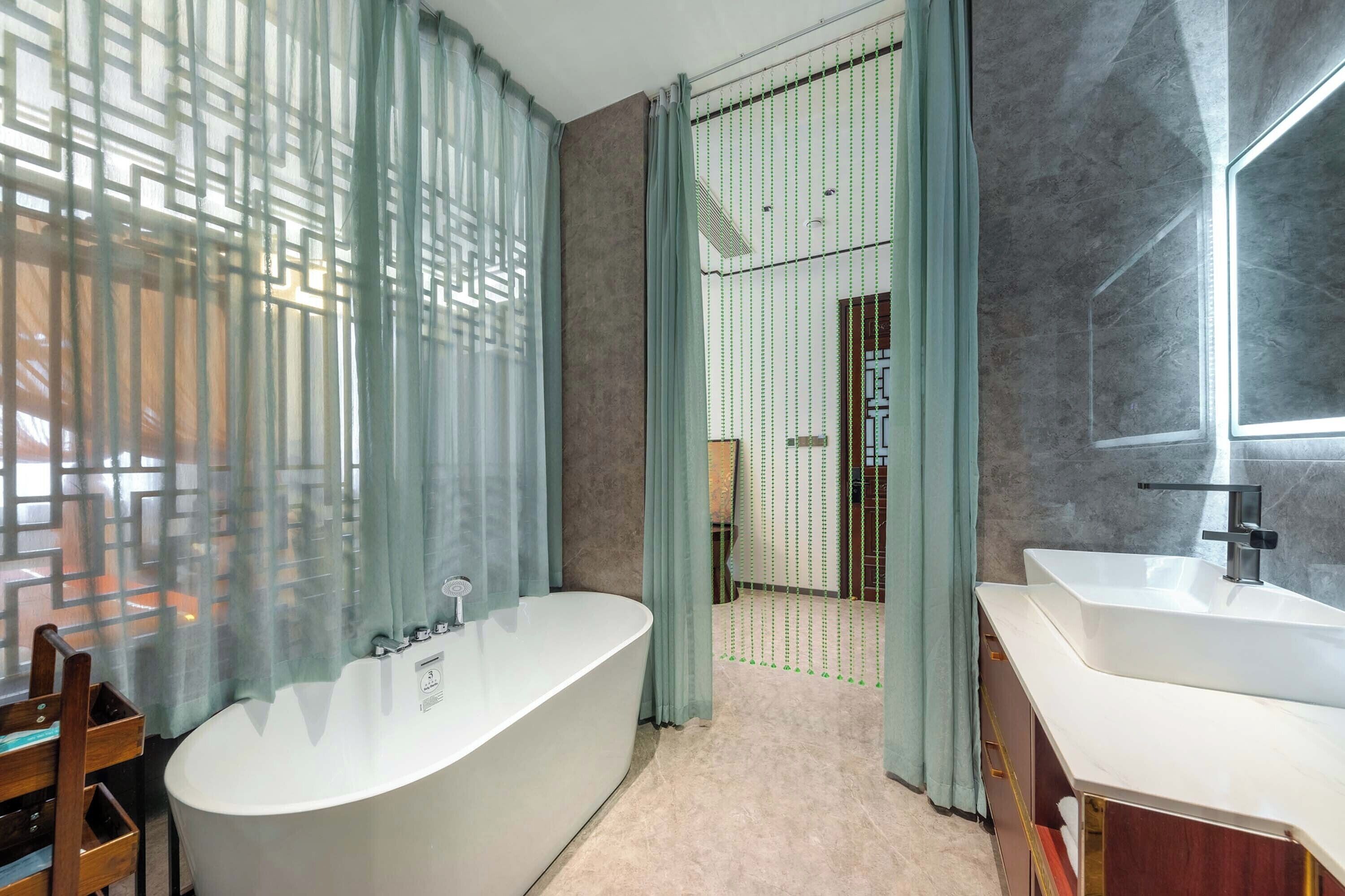 Un baño moderno con una bañera independiente, dos lavamanos y una zona de ducha.