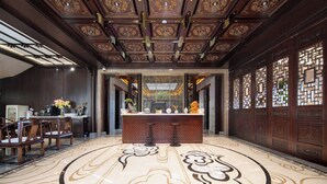 Um hall de entrada com balcão de recepção, área de estar e teto decorativo.