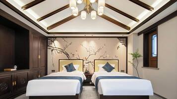 A hotel room with two beds, a large chandelier, a wall mural, and a window.
