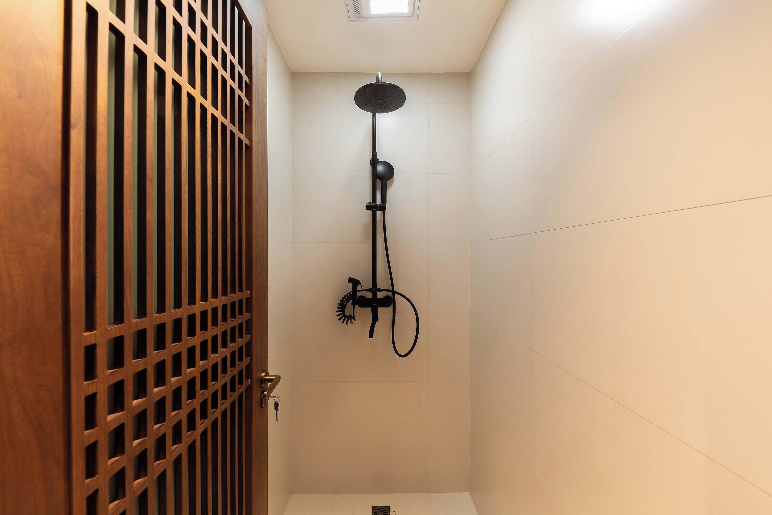 A shower with a handheld showerhead, a wall-mounted faucet, and a control panel.