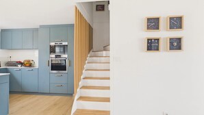 Eine moderne Küche mit blauen Schränken, einer Holztreppe und vier gerahmten Uhren an der Wand.